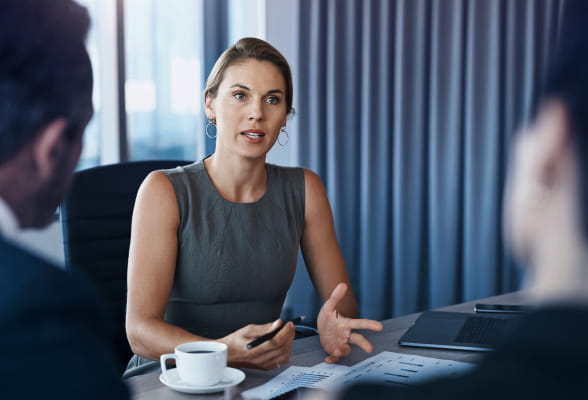 Woman engaged in a business meeting with two men, discussing strategic financial decisions