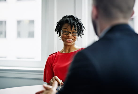 A woman in red engages in a conversation with a man, discussing strategies to prepare for interest rate movements and protect financial interests with StoneX interest rate swaps